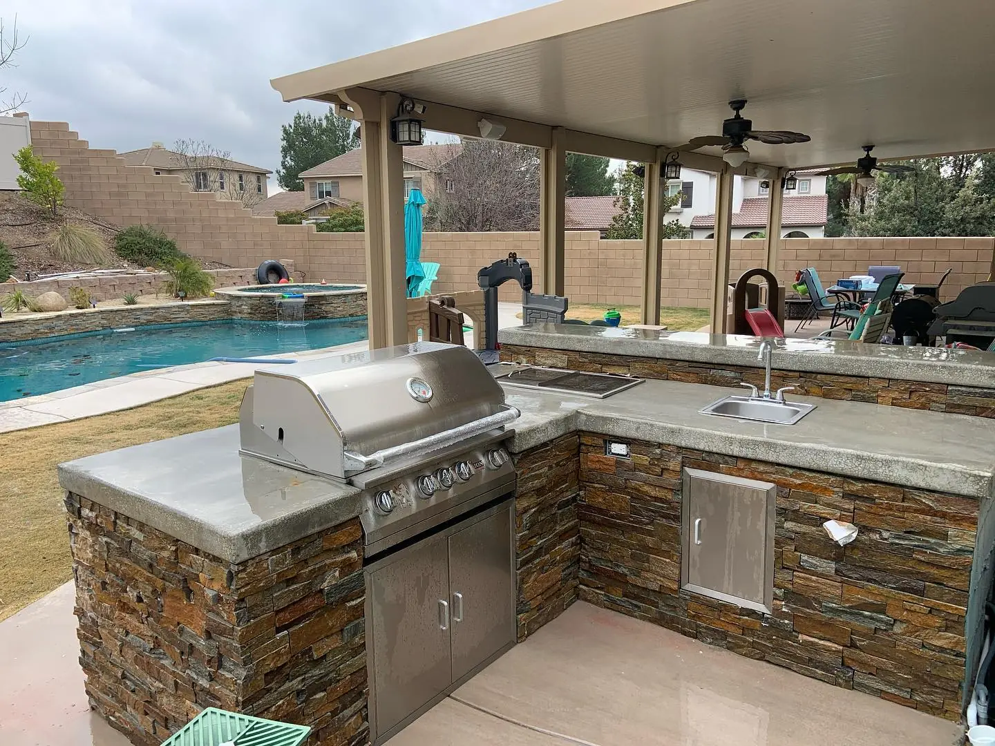 Stacked-stone outdoor kitchen beside a pool
