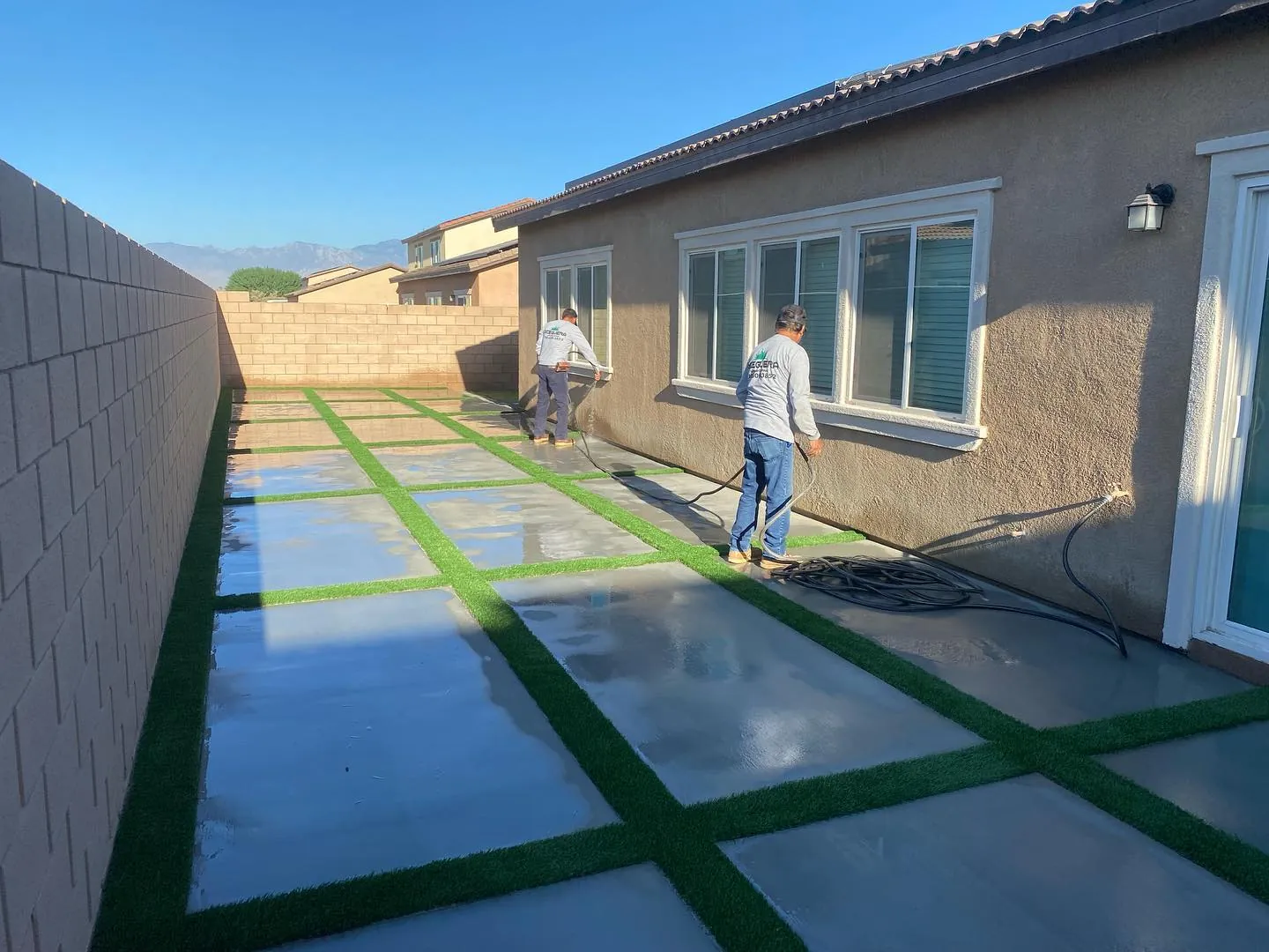 Concrete pads with artificial turf strips between them in a modern side yard