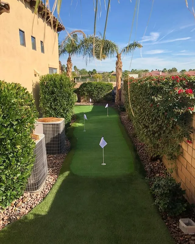 Backyard artificial putting green with flags, hedges and palms